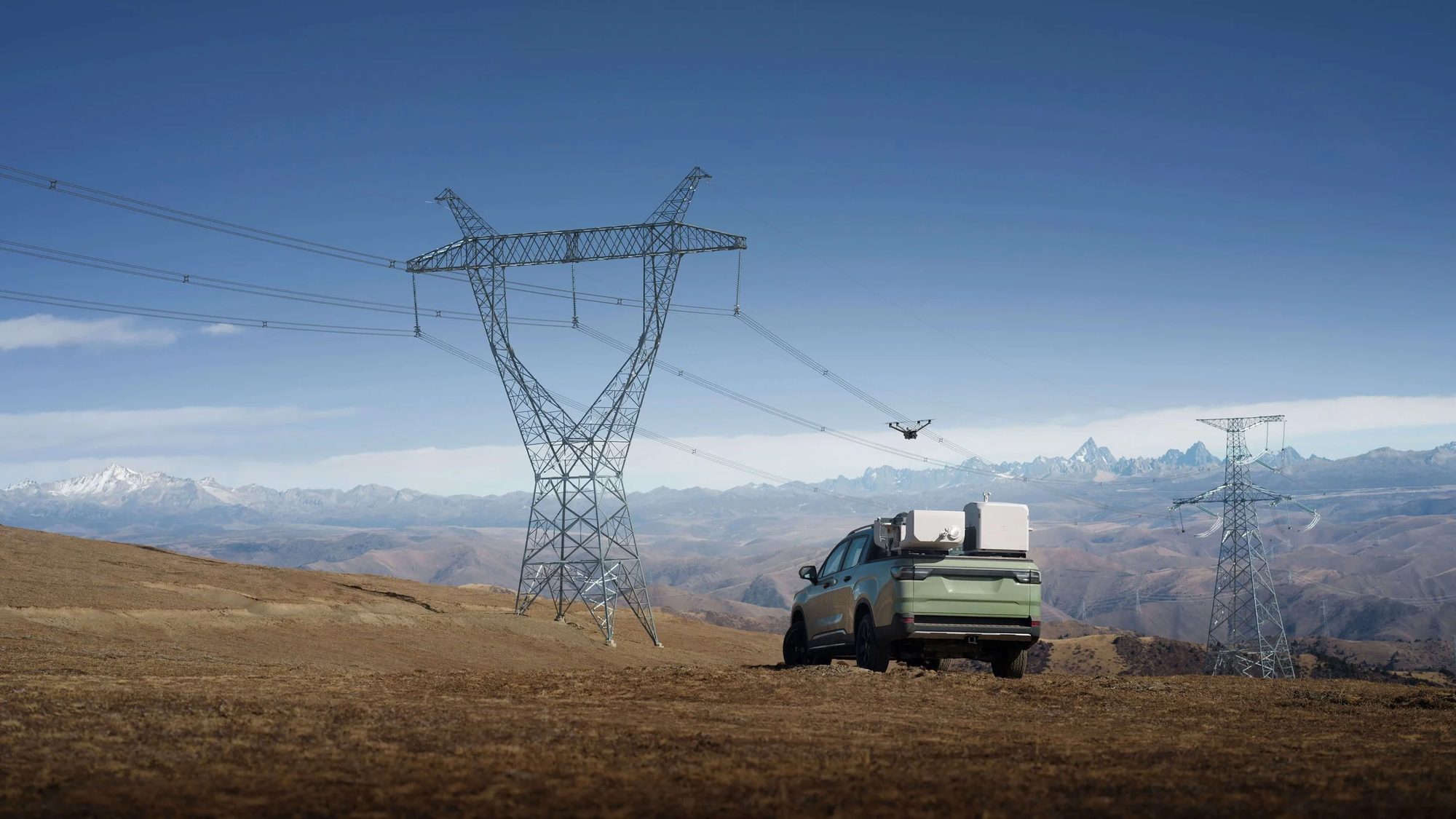 DJI Dock 3 mounted on a vehicle beside transmission towers in open country